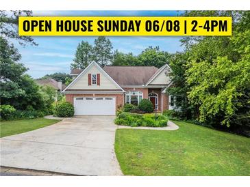 Charming brick home with a manicured lawn, mature trees, and a welcoming two-car garage at 635 Piping Rock Pt, Lawrenceville, GA 30043