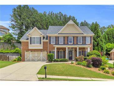 Charming two-story brick home features a manicured front yard, attached garage, and classic architectural details at 5865 Trailwood Ct, Suwanee, GA 30024