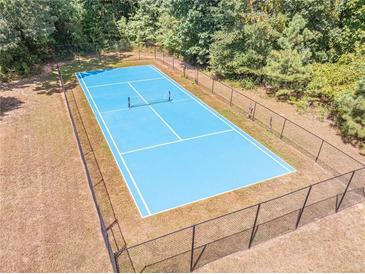 Aerial view of fenced in blue tennis court surrounded by lush landscaping at 2740 Bountiful Pl, Lawrenceville, GA 30045