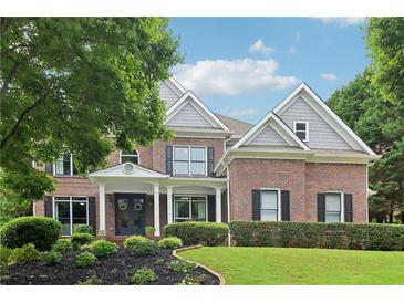 Charming two-story brick home with a landscaped front yard, dark shutters, and a welcoming covered porch entry at 4085 Hillcrest View Ct, Suwanee, GA 30024