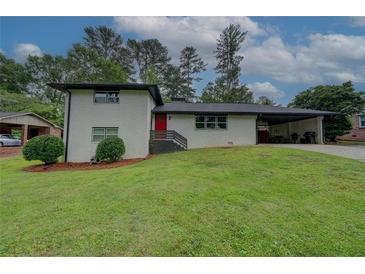 Charming two-story home featuring a red front door, white brick, a carport, and a lush green front yard at 2324 Ithica Se Dr, Marietta, GA 30067