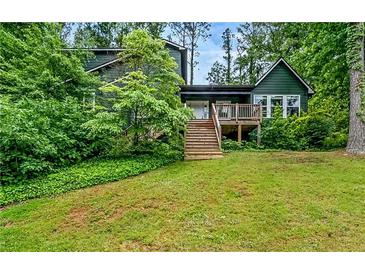 Charming two-story home with a wooden deck and stairs, surrounded by lush green landscaping at 1033 Justice Nw Ln, Acworth, GA 30102