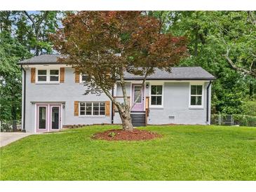 Charming home featuring a grey brick facade, well-manicured lawn, and a beautiful tree in the front yard at 3034 Barksdale Cir, Atlanta, GA 30344