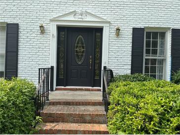 Charming front door with decorative glass and brick steps, framed by lush green bushes at 1159 Aurora Ct, Atlanta, GA 30338