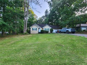 Quaint home featuring green lawn, mature trees, complementary green trim, and an attached two-car garage at 273 Apalachee Church Rd, Auburn, GA 30011