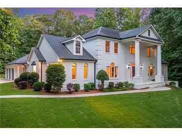 Elegant white brick home featuring a manicured lawn and lush landscaping at 5145 Saddlebred Ln, Cumming, GA 30028