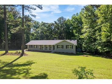 Charming ranch-style home with a large front yard and covered front porch surrounded by mature trees at 6133 Post Rd, Douglasville, GA 30135