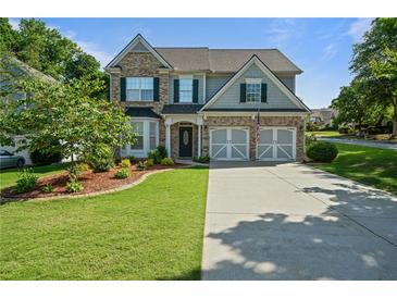Charming two-story home with a well-manicured front lawn and a driveway leading to a two-car garage at 700 Mill Creek Cv, Canton, GA 30115