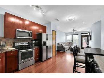 Modern kitchen featuring stainless steel appliances and rich wood cabinetry, seamlessly flowing into the living area at 898 Oak Sw St # 3204, Atlanta, GA 30310
