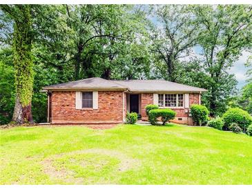 Charming brick home featuring a lush green lawn and mature trees providing ample shade and curb appeal at 1913 Flintwood Se Dr, Atlanta, GA 30316
