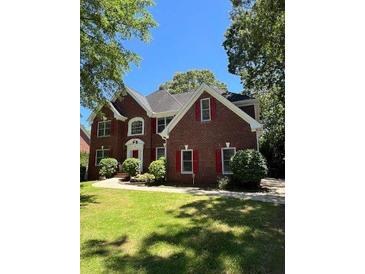 Traditional two-story brick home featuring red shutters and a well-manicured front lawn at 5190 Beech Forest Sw Dr, Lilburn, GA 30047