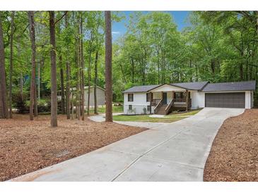 Charming home with a long driveway and a beautifully landscaped front yard surrounded by mature trees at 3455 Broxton Mill Way, Snellville, GA 30039