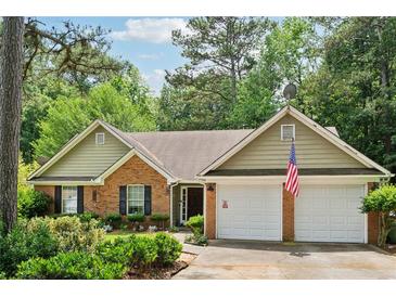 Charming one-story brick home featuring an attached two-car garage and lush, mature landscaping at 2080 Bankston Cir, Snellville, GA 30078