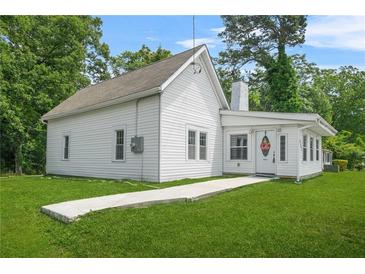 Charming cottage-style home featuring white siding and a well-manicured front lawn at 6802 Ida St, Lithonia, GA 30058