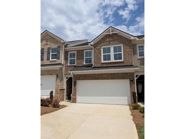 Brick townhome exterior with a two-car garage and well-manicured landscaping for a polished look at 934 Elwood St, Dacula, GA 30019