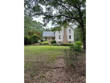Charming two-story home featuring a covered front porch, brick chimney and large front lawn at 2377 Centerville Rosebud Rd, Loganville, GA 30052