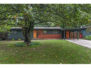 Charming single-story home featuring a well-manicured lawn and mature trees with a brick accent and cheerful orange front door at 3580 Raymond Dr, Atlanta, GA 30340