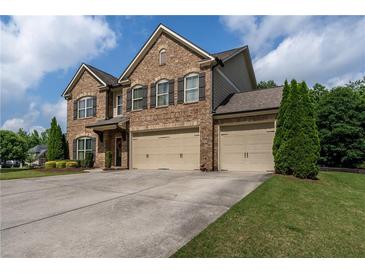 Stunning brick two-story home with a three-car garage and well-manicured lawn at 4305 Hunters Walk Way, Cumming, GA 30028