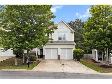Charming townhome featuring a two-car garage and well-maintained lawn at sunset at 720 Mountain Laurel Dr, Canton, GA 30114