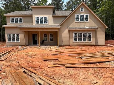 Two-story home featuring beige siding and multiple windows, set against a backdrop of lush trees at 7947 Post Rd, Winston, GA 30187