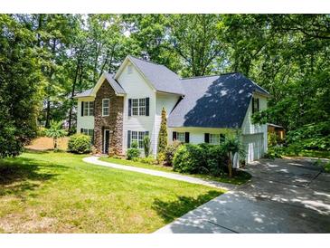 Charming two-story home with stone accents and a well-manicured lawn surrounded by mature trees at 97 Coral Dr, Whitesburg, GA 30185