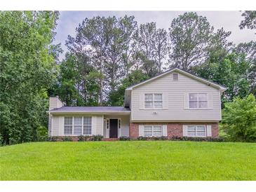 Charming two-story home with a well-manicured lawn and lush surrounding trees at 803 Cedar Lake Se Dr, Conyers, GA 30094