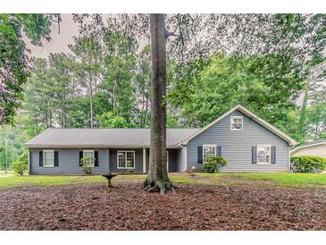 Charming home with grey siding and a well-manicured lawn surrounded by mature trees at 4248 Wellington Hills Ln, Snellville, GA 30039