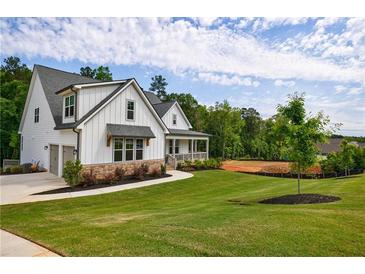 Beautiful white farmhouse with manicured lawn and stone accents at 130 Lapis Lake Pt, Fayetteville, GA 30215