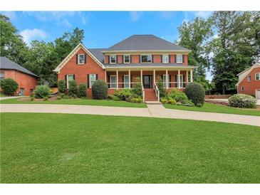 Charming two-story brick home with a large front lawn, covered porch, and manicured landscaping at 2535 Winthrope Way, Lawrenceville, GA 30044