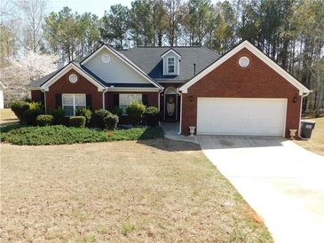 Charming brick home with a well-manicured lawn, lush landscaping, and a two-car garage at 40 Pebble Brooke Ct, Covington, GA 30016