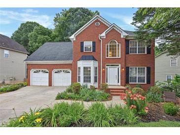 Charming brick home featuring a two-car garage, manicured landscaping, and a welcoming front entrance at 2018 Township Dr, Woodstock, GA 30189