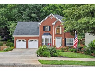 Charming two-story brick home with a two-car garage, manicured lawn and colorful flowerbeds at 2018 Township Dr, Woodstock, GA 30189