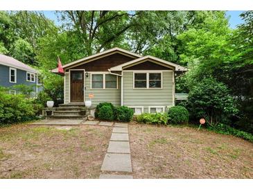Charming bungalow with light green siding, stone walkway, and mature trees at 677 Holmes Nw St, Atlanta, GA 30318