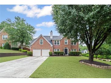 Traditional brick home featuring a well-manicured lawn and an attached two-car garage at 10735 Pinewalk Forest Cir, Alpharetta, GA 30022