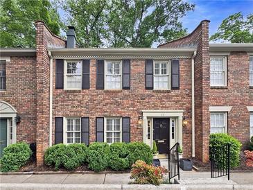Charming brick townhouse featuring symmetrical design, black shutters, and manicured landscaping at 70 Old Ivy Ne Rd # 57, Atlanta, GA 30342