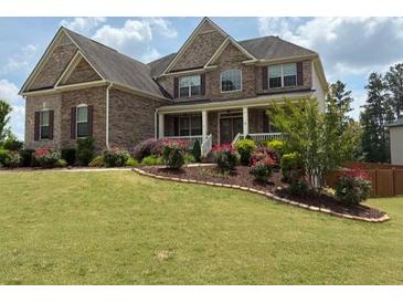 Beautiful two-story brick home with well-manicured lawn and colorful landscaping at 6585 Canyon Cv, Cumming, GA 30028