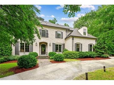 Charming brick home featuring dark shutters, manicured landscaping, and brick-paved driveway at 2115 Howell Mill Nw Rd, Atlanta, GA 30318