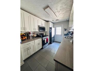 Galley kitchen featuring white cabinets, grey tile flooring, and stainless steel appliances at 4312 Idlewood Ln, Tucker, GA 30084