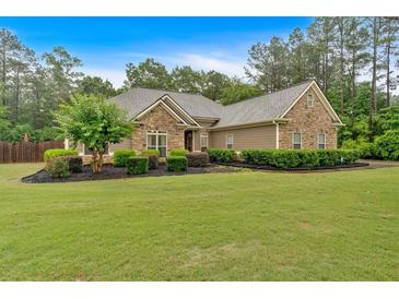 Well-maintained single-story home with stone accents, manicured landscaping, and lush green lawn at 7030 Mandevilla Ln, Douglasville, GA 30135
