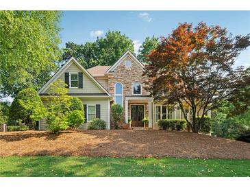Charming home showcasing a stone and siding facade, well-manicured lawn and a mature landscape at 4750 Freeport Bay Ne, Roswell, GA 30075