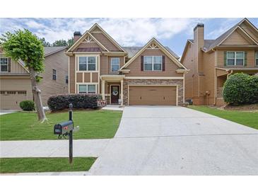 Inviting two-story home featuring a stone accents, a two-car garage, and a well-manicured front lawn at 1267 Castleberry Dr, Buford, GA 30518