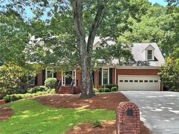 Charming brick home with a two-car garage, dormer windows, mature trees and well-maintained landscaping at 2010 Pearwood Path, Roswell, GA 30076