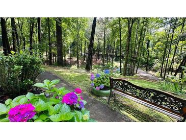 Inviting garden path featuring colorful flowers and a quaint bench, surrounded by lush greenery and mature trees at 2985 Heather Stone Way, Lawrenceville, GA 30043