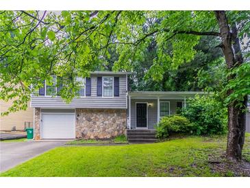 Charming split-level home with a stone facade, attached garage, and a well-manicured lawn at 4766 White Oak Path, Stone Mountain, GA 30088
