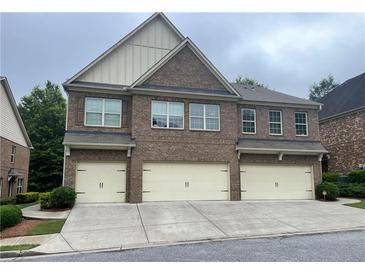 Townhome exterior with a three-car garage, brick facade, and covered entrance on a cloudy day at 805 Pleasant Hill Nw Rd # 53, Lilburn, GA 30047