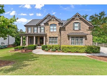 Beautiful stone and brick home with a manicured lawn, established bushes, and three-car garage at 6625 Baywood Run, Cumming, GA 30041
