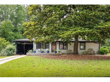 Charming single-story home features a mature tree and a well-manicured front lawn at 1195 Russell Dr, Decatur, GA 30030