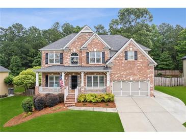 Charming brick two-story home with a welcoming front porch and a well-manicured lawn at 927 Ivey Chase Pl, Dacula, GA 30019