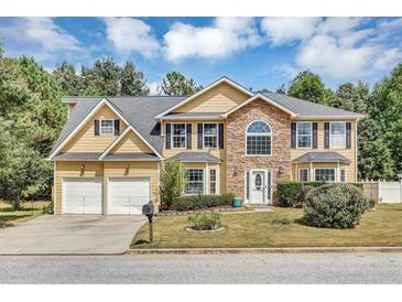 Inviting two-story home featuring stone accents, a two-car garage, and well-manicured landscaping at 5115 Estonian Dr, Fairburn, GA 30213