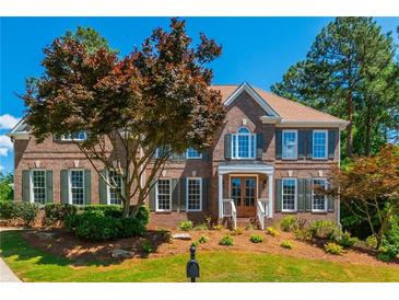 Stately two-story brick home with lush landscaping, beautiful lawn, and a charming, covered front porch at 1096 Bridge Mill Ave, Canton, GA 30114
